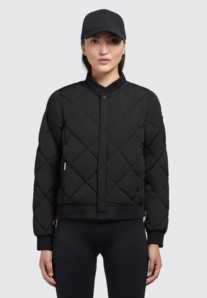 Mustat tikatut bomber-takit, joissa on pyöreä kaulus, etupuolella napitus ja ribbed hihansuut. Vietetty mustien legginsien päällä, jossa on sivu-logo-tagi.