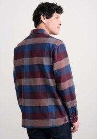 Camicia di flanella a quadri con quadrati blu, bordeaux e beige; maniche lunghe; polsini con bottoni; vestibilità rilassata; texture liscia.