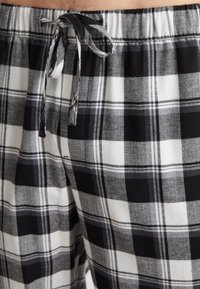 Svartvitrutig pyjamashorts i mjukt tyg, med dragsko i midjan och en kombination av stora och små rutmönster.