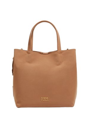 Beżowa torba tote wykonana z gładkiego materiału, z dwoma uchwytami na górze, złotym logo marki oraz minimalistycznym designem bez widocznych zapięć czy wzorów.