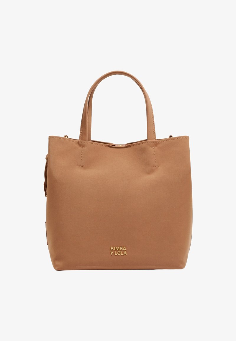 Beżowa torba tote wykonana z gładkiego materiału, z dwoma uchwytami na górze, złotym logo marki oraz minimalistycznym designem bez widocznych zapięć czy wzorów.