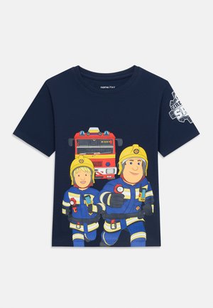 Chemise bleu marine avec deux pompiers dessinés animés portant des casques jaunes courant devant un camion de pompiers rouge, emblème de feu sur la manche droite.
