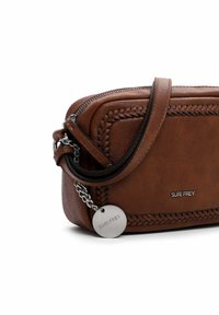 Borsa a tracolla in pelle marrone con dettagli intrecciati, minuteria in argento, chiusura a zip e un'etichetta circolare. Forma rettangolare compatta.