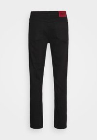 Pantalones de mezclilla negra con un diseño ajustado, que cuentan con una etiqueta roja de HUGO en la parte trasera. Muestra un estilo estándar de cinco bolsillos y un corte recto.