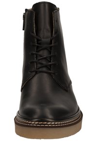 Mustat nahkasaappaat nilkkapituisina, pyöreällä varvantilalla, etusiteillä, sivuvetoketjulla, ruskealla pohjalla ja erottuvilla ompeluvarusteilla.