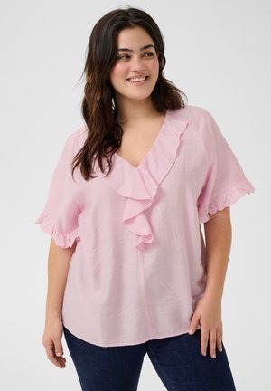 Light pink blouse with ruffled neckline and short sleeves, made of soft fabric. V-neck design with a relaxed fit, paired with dark jeans.