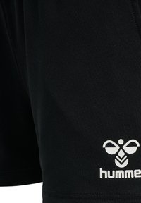 Zwarte sportshorts van glad synthetisch materiaal; heeft een geborduurd wit logo aan de linkerkant.