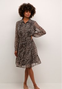 Robe chemise à imprimé léopard avec des manches longues, taille cintrée, jupe à volants, faite de tissu léger, avec un col et une patte de boutonnage.
