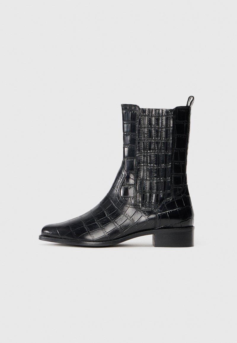 Black ankle boots featuring a crocodile leather texture, pointed toe, low stacked heel, and elastic side panels for easy wear.