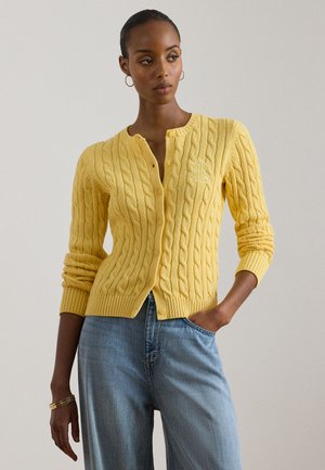 Gul kabelstrikket cardigan med rund hals, knappelukking foran og ribbestrikket kant. Har en brodert logo på brystet.