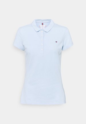 Light blue women's polo shirt with short sleeves, four white buttons, a collar, and a small Tommy Hilfiger logo on the chest.