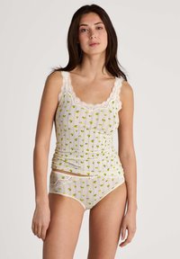 Ensemble de lingerie léger à pois crèmes avec des motifs floraux verts. Le haut présente un décolleté en dentelle festonné ; le bas s'accorde avec des accents en dentelle.