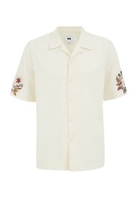 Camisa de manga corta, abotonada, en tela color crema, con bordados florales en las mangas en colores suaves. Dobladillo recto.