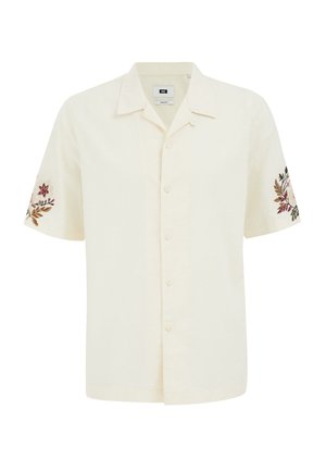 Kratki rukavi, košulja na gumbe od kremaste tkanine, sa cvjetnim vezom na rukavima u prigušenim bojama. Ravni rub.