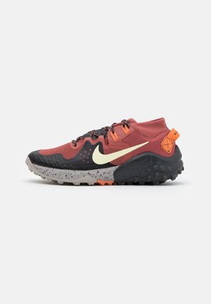 Chaussure de trail avec dessus rouge, semelle mouchetée noire et grise, swoosh Nike jaune, languette de talon orange, et lacets noirs à motifs.