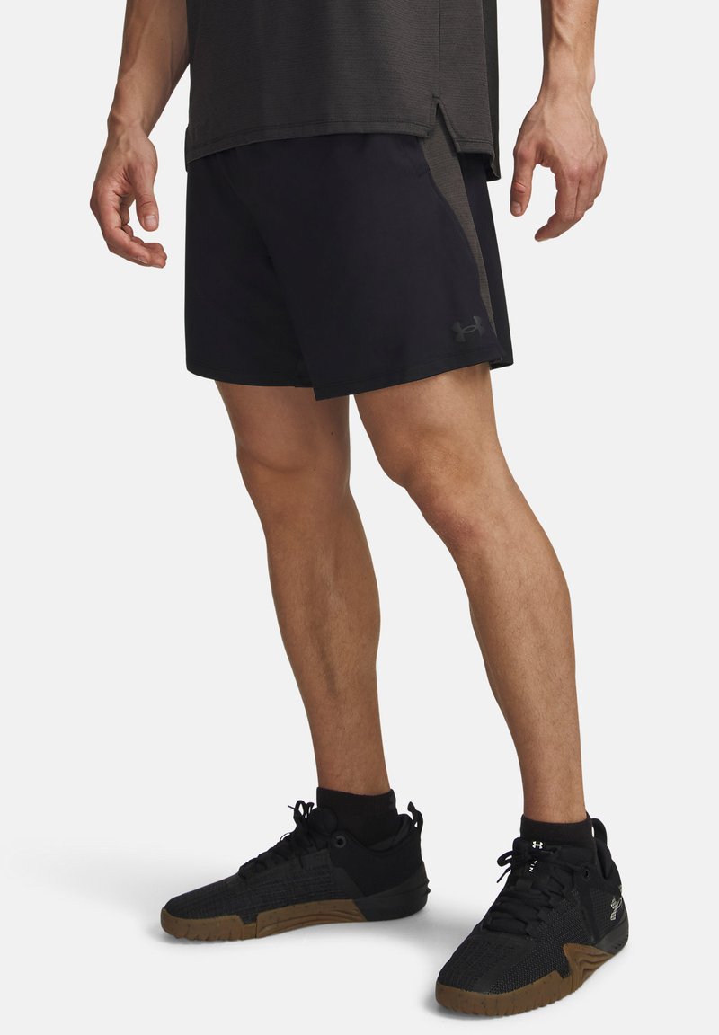 Μαύρα αθλητικά σορτς με λείο ύφασμα και πλευρικές λεπτομέρειες. Φοριούνται με μαύρα παπούτσια αθλητικά με πλέγμα στο επάνω μέρος και ελαστική σόλα.