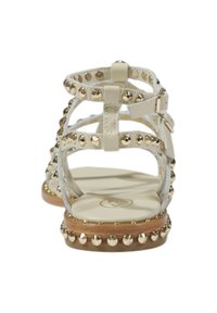 Sandales blanches à brides avec clous dorés, semelle en bois plate et boucle réglable. Dessus léger et texturé avec plusieurs brides.