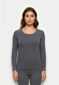 Maglietta grigia a maniche lunghe realizzata in un tessuto morbido e elasticizzato, con scollatura rotonda e orlo che si estende leggermente al di sotto della vita.