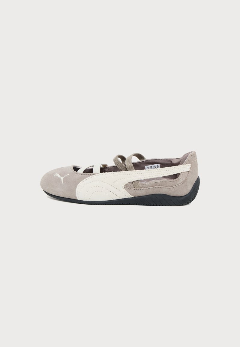 Ballerine plate en daim brun clair avec logo Puma blanc, bande latérale blanche, sangles élastiques et semelle en caoutchouc noire.