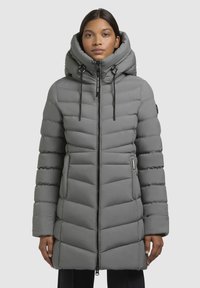 Grijze gewatteerde parka met een hoge kraag, ritssluiting, verstelbare capuchon en zijzakken. Kenmerkt zich door een chevronquiltpatroon en een elegante stof.