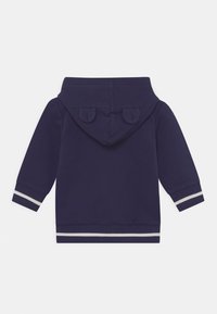 Felpa blu navale con una texture morbida, presenta un cappuccio arrotondato con accenti a forma di orecchie e polsini e vita a strisce bianche.