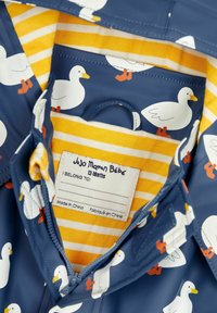 Un imperméable bleu avec un motif de canard, doté d'une doublure intérieure à rayures jaunes. Comprend une étiquette cousue pour l'identification personnelle.