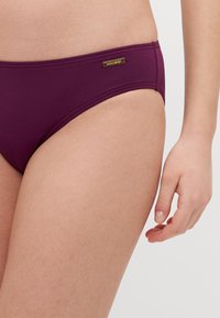 Culotte da bagno color bordeaux realizzate in tessuto liscio con vita bassa. Presentano un sottile etichetta del marchio sul lato e dettagli delle cuciture per una maggiore struttura.