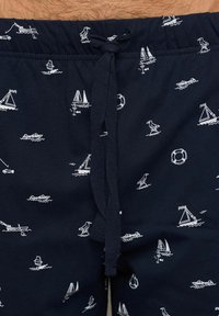 Pantaloni da bagno blu navy con stampa bianca a tema nautico che include barche, uccelli e salvagenti; presenta una vita elastica con cordoncino.