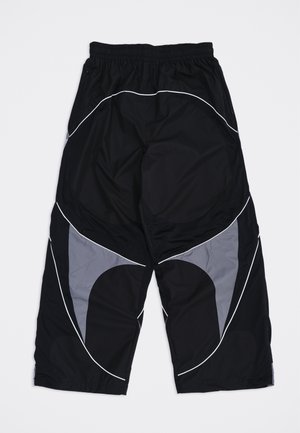Pantaloni neri e grigi a vestibilità ampia con elastico in vita e dettagli di piping bianco curvo sulle gambe, distesi su uno sfondo bianco.