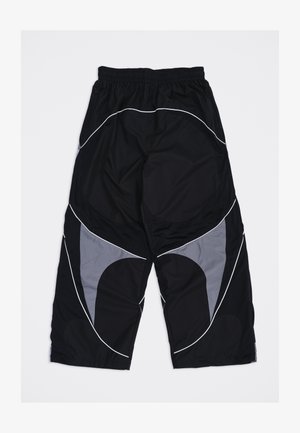 Pantaloni neri e grigi a vestibilità ampia con elastico in vita e dettagli di piping bianco curvo sulle gambe, distesi su uno sfondo bianco.