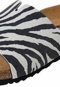 Zebra print sandal med et sort og hvidt mønster, der har et blødt overmateriale og en tekstureret fodseng for komfort.