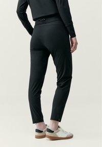 Čierne atletické nohavice so slim fit strihom, s hladkou textúrou a zipsom na členkoch. Štýlované v minimalistickom dizajne, v kombinácii s pohodlnými teniskami.