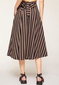 Randig midi kjol i lätt fabric, med en svart bas och rosa och vita ränder, en knuten midja och sidofickor.