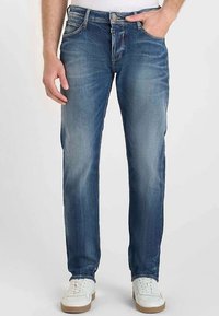 Blå denimjeans med smal passform, i ljus tvätt, subtila blekningsdetaljer och standarddesign med fem fickor. Matchas med vita sneakers.