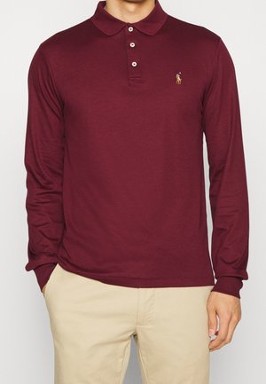 Bordowa koszulka polo z długim rękawem, kołnierzykiem i trzema guzikami. Na lewej piersi haftowane logo. Miękka, gładka faktura materiału.