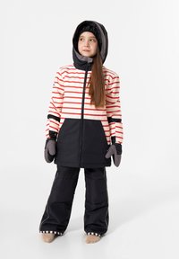 Winteroutfit für Mädchen mit einer gestreiften rot-weißen Jacke und einem schwarzen unteren Abschnitt, kombiniert mit schwarzen Schnee-Hosen und grauen Handschuhen.