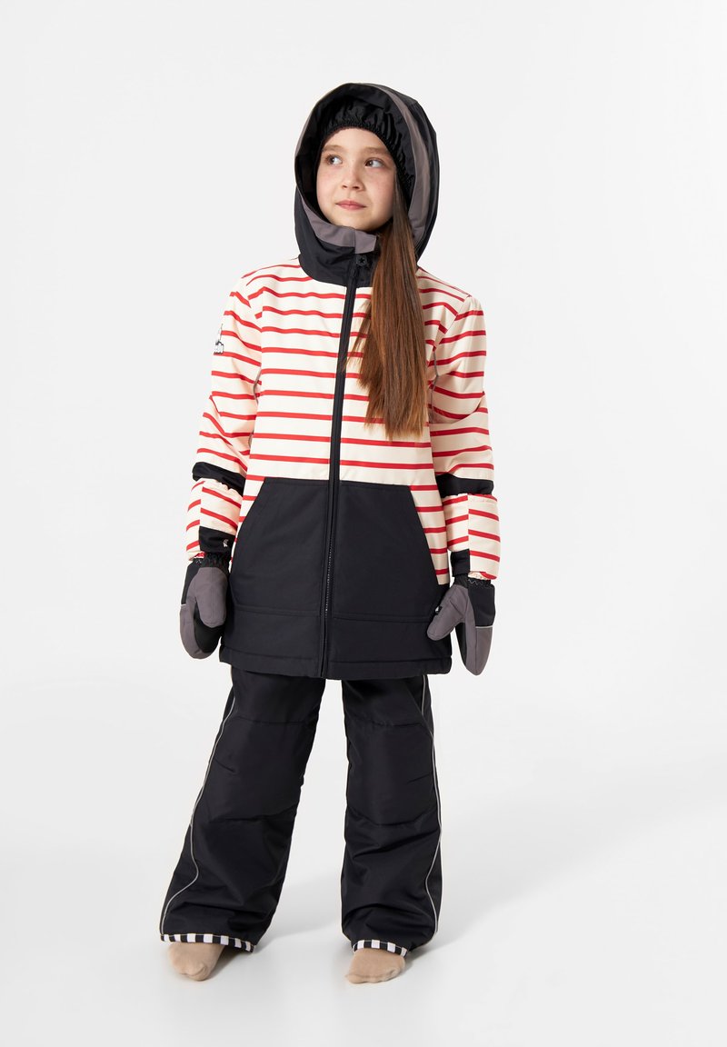 Winteroutfit für Mädchen mit einer gestreiften rot-weißen Jacke und einem schwarzen unteren Abschnitt, kombiniert mit schwarzen Schnee-Hosen und grauen Handschuhen.