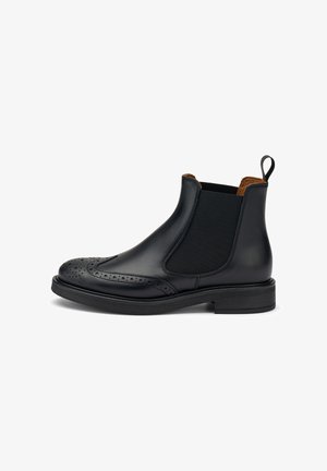 Stivale Chelsea in pelle nera con pannelli elastici laterali, dettagli brogue sulla punta e tacco basso impilato. La superficie è liscia con una finitura opaca.