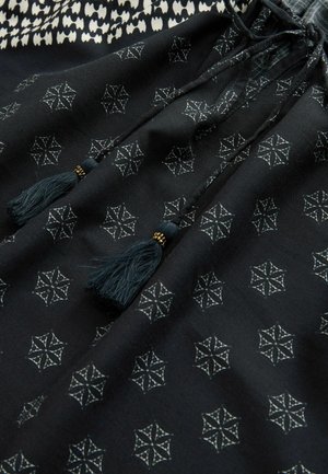 Fekete szövet fehér csillagmintákkal, húzózsinóros zárással és két sötét rojttal. Puha tapintású, enyhe fényű.