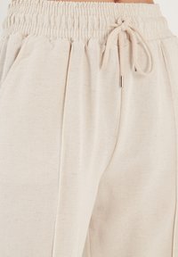 Beige linnen joggerbroeken met een elastische tailleband, trekkoordsluiting en zijzakken. Gestructureerde stof met subtiele variaties.
