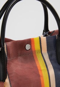 Gestreepte tote bag met geweven textuur, in de kleuren bruin, geel, oranje en blauw. Zwarte leren handvatten en een metalen drukknoopsluiting.