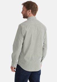 Gemustertes grünes Langarmhemd mit Kragen, Knopfmanschetten und einem strukturierten Stoff. Sichtbare Nähte auf der Rückseite. Lockere Passform.