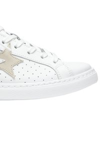 Sneaker bianca con design perforato, stella in suede beige come accent, punta rotonda e lacci bianchi. Suola in gomma testurizzata per una buona tenuta.