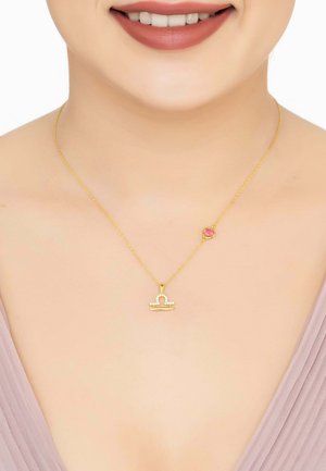 Gold necklace featuring a Libra symbol pendant adorned with small white stones and a pink accent, suspended from a delicate chain.