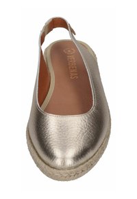 Zapato slingback metálico dorado con parte superior de cuero texturizado, correa elástica beige y suela de yute trenzado. Diseño plano y de punta redonda.