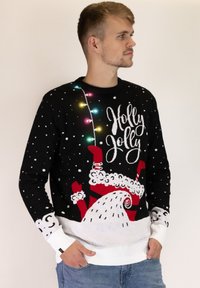 Schwarzer, gestrickter Weihnachtspullover mit weißen Schneeflocken, bunten Lichtelementen und einem Design von Santa mit dem Text "Holly Jolly".