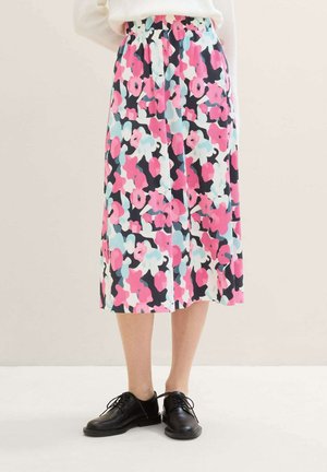 Jupe midi florale en rose, bleu et noir. Fabriquée en tissu texturé avec des plis et une taille élastique. Associée à des chaussures noires.