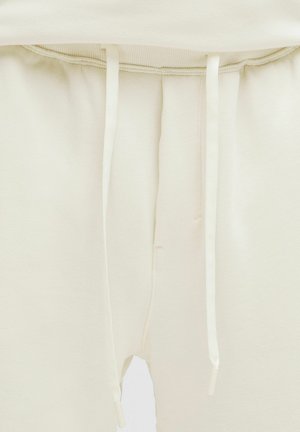 Šviesiai kreminės spalvos laisvalaikio kelnės iš minkštos medžiagos. Turi elastingą juosmenį su raišteliais ir šonines siūles laisvesniam prigludimui.