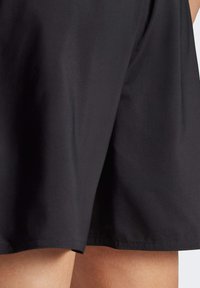 Black athletic shorts made of smooth, lightweight fabric. Features a subtle sheen, with clean stitching and a straight hemline.