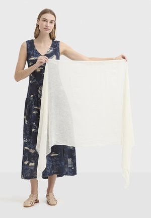 Leichter cremefarbener Schal, gehalten von einer Person, aus weichem Stoff, mit transparenter Textur, rechteckiger Form und ausgefransten Kanten.